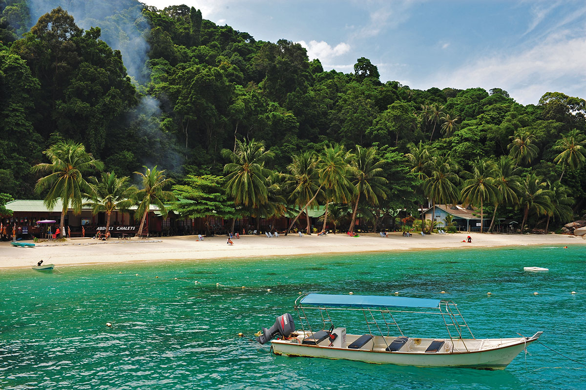 Boot in azuurgekleurde zee voor strand van Perhentian Eilanden.