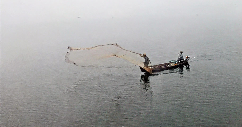 Visser werpt net uit op het meer bij de U-Bein Bridge.