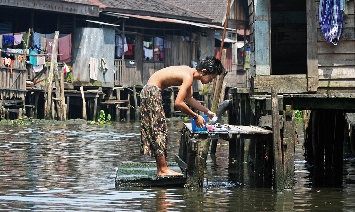 Man wast zich bij huis op het water in Banjarmasin.
