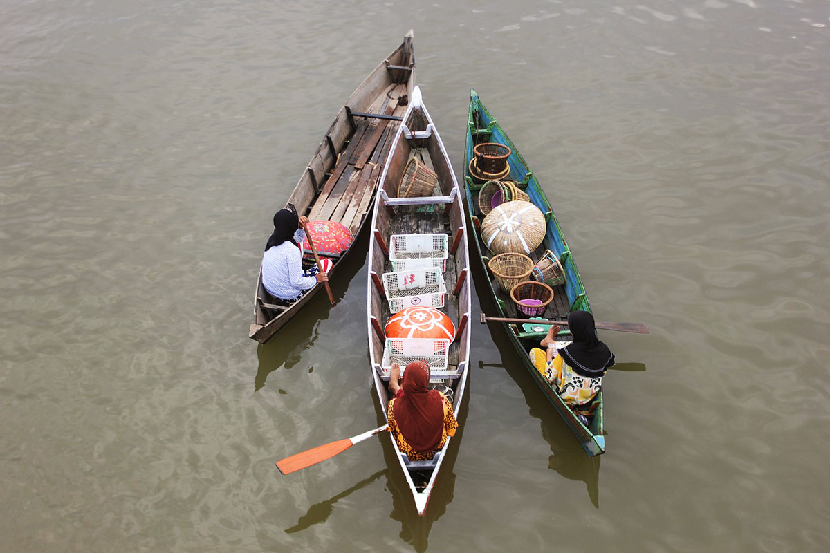 Vrouwen roeien in smalle boot bij Banjarmasin.