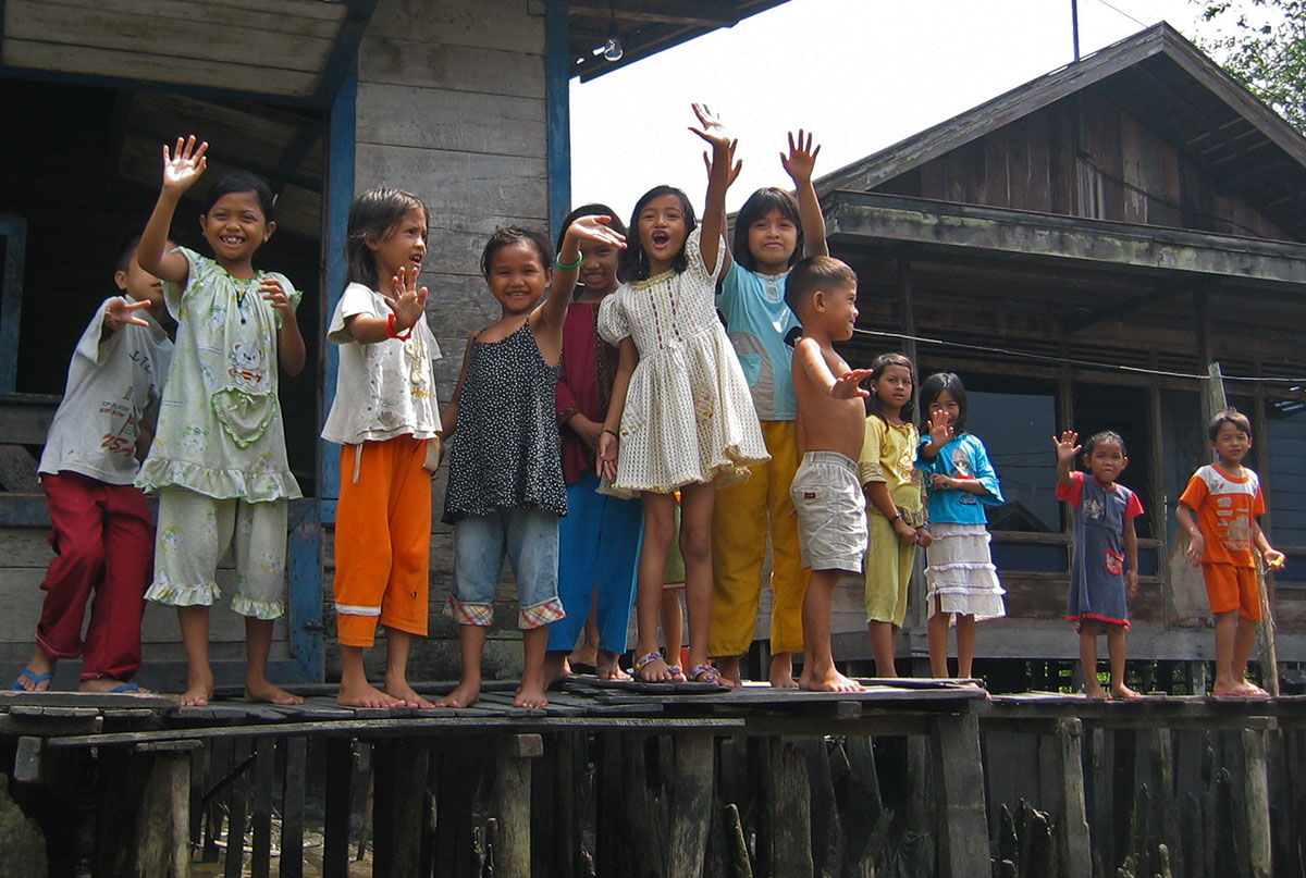 Zwaaiende meisjes op houten vlonder in Banjarmasin.