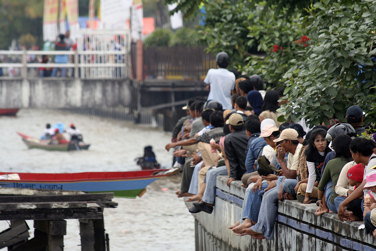 Mensen zittend op muur bij de rivier in Samarinda.