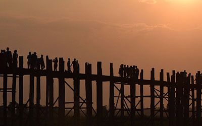 Over de U-Bein Bridge lopen bij zonsondergang