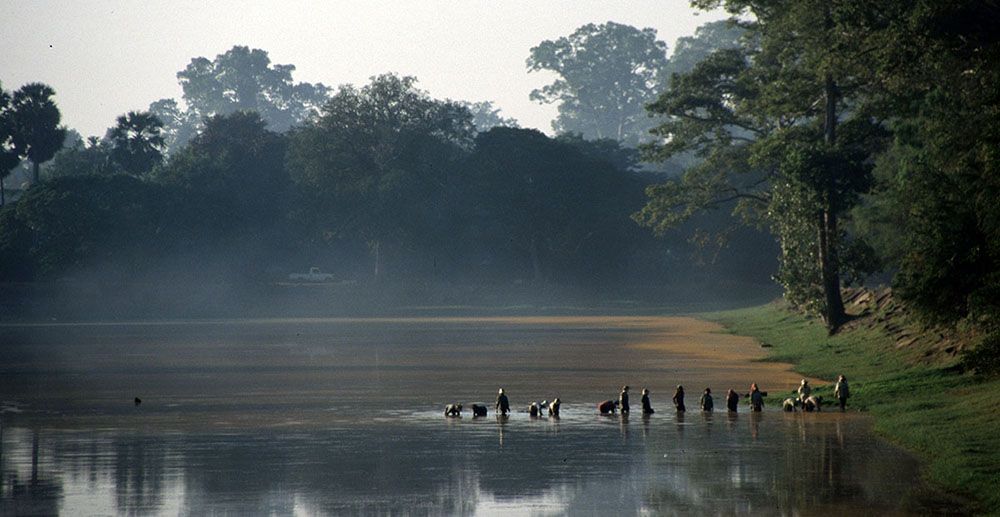 Lokale bevolking waadt door water bij Angkor Wat, hoofdattractie van Cambodja.