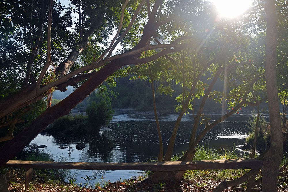 De zon schijnt door de bomen bij rivier in de buurt van Ban Lung.