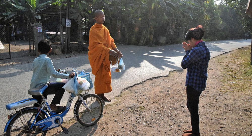 Monnik krijgt eten van lokale bewoonster bij Battambang.