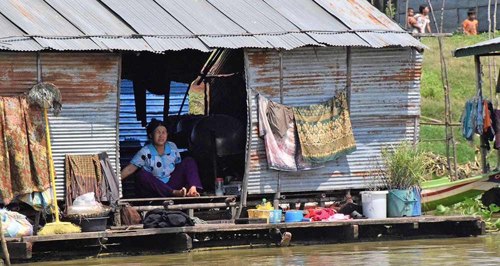 Vrouw zit in eenvoudig huisje langs de rivier bij Siem Reap.