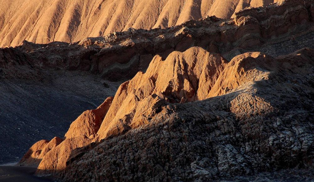 De zon kleurt de rotsen in Valle de la Luna.