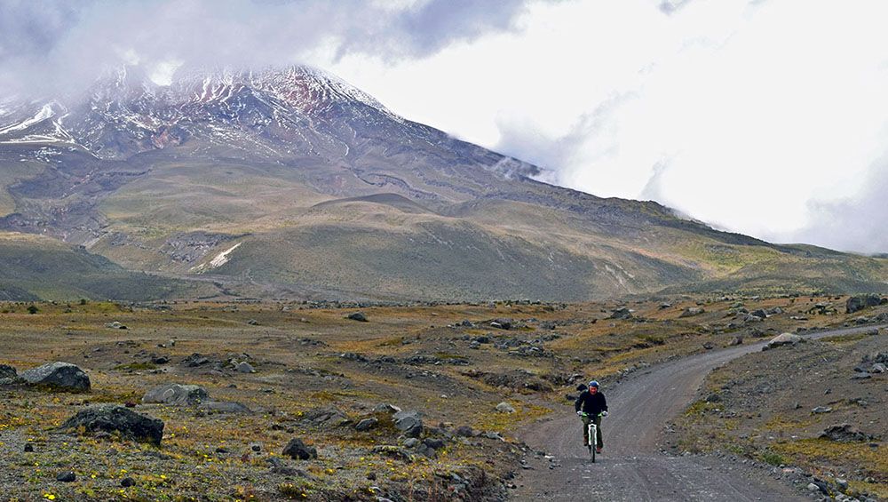 Mountainbiker met op de achtergrond de Cotopaxi vulkaan.