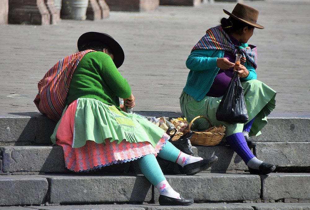 Kleurrijke vrouwen zitten op de stoep in Peru met hun handelswaar