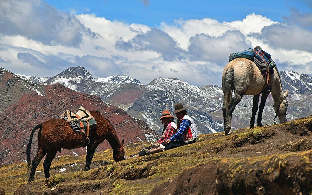 Peruaanse vrouwen met paard rusten uit bij Rainbow Mountain