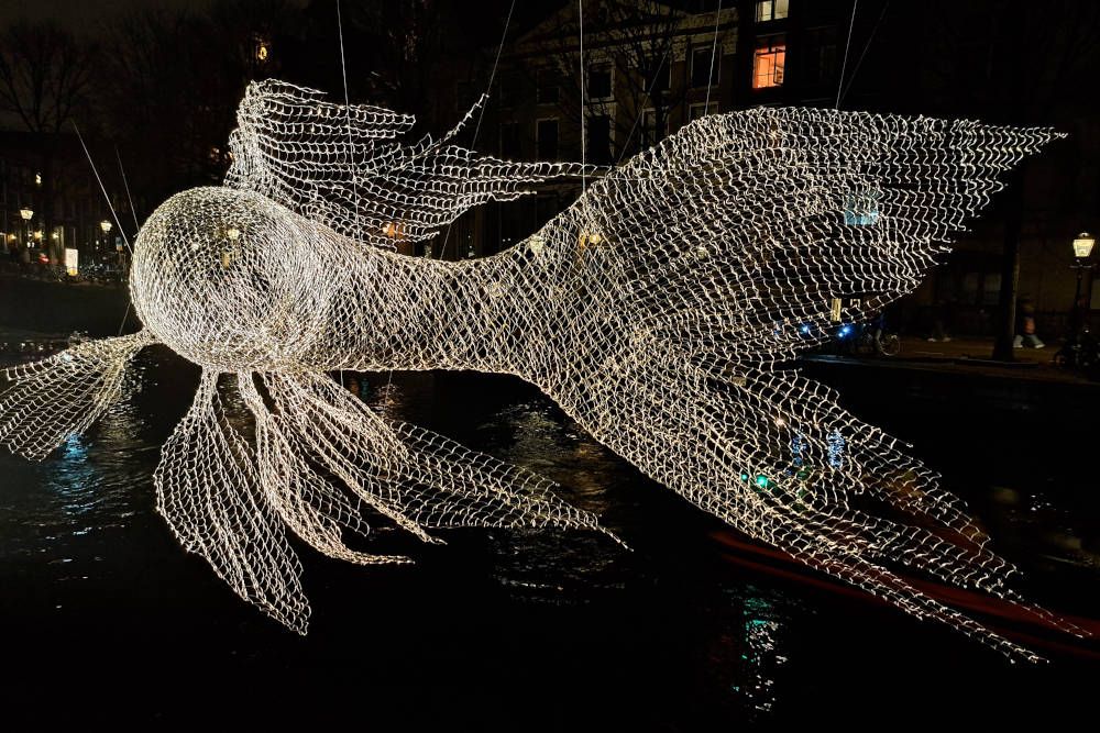 Zwevende paardenbloemen boven gracht bij Amsterdam Light Festival.